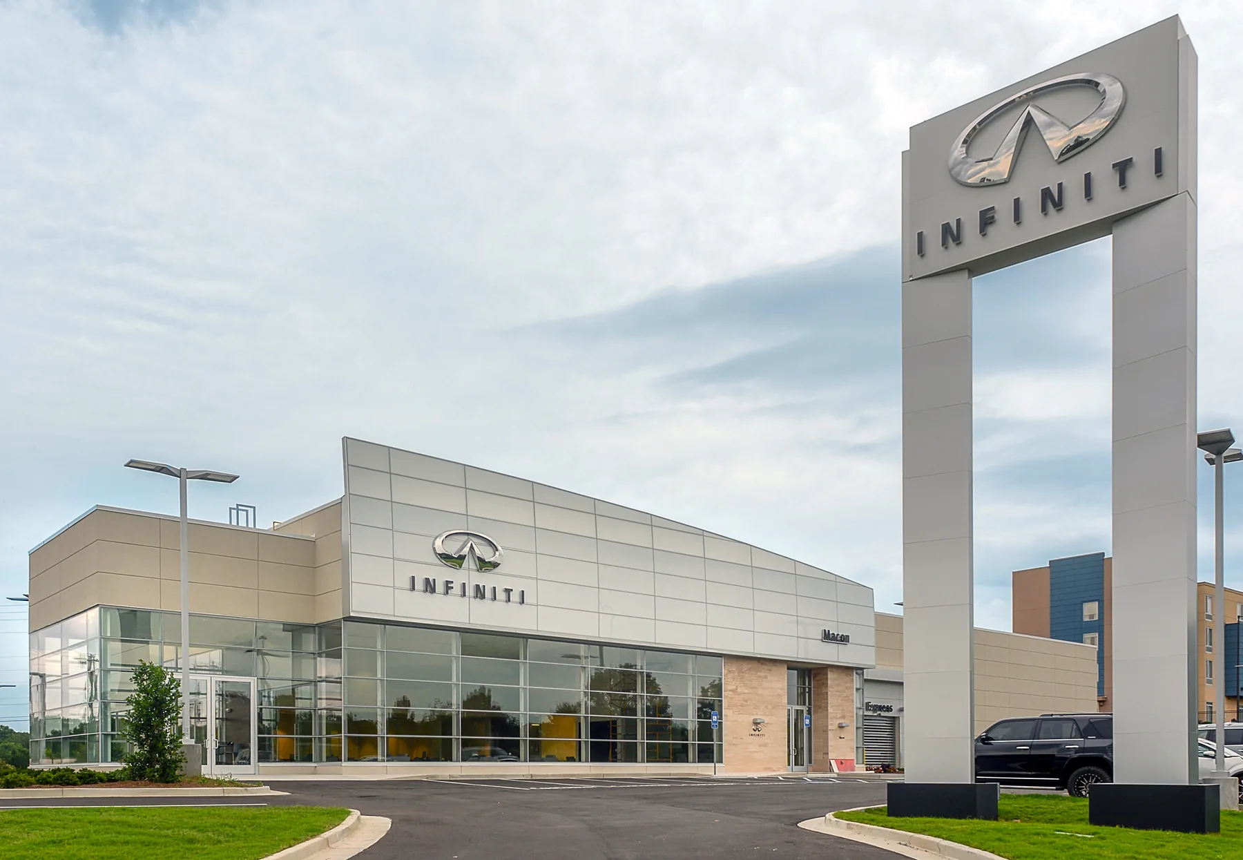 Glass-fronted INFINITI automotive dealership and roadside pylon in Macon